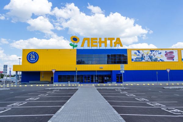 Фасад супермаркета Лента, фирменные цвета и логотип, крупный план здания с парковкой, летний день