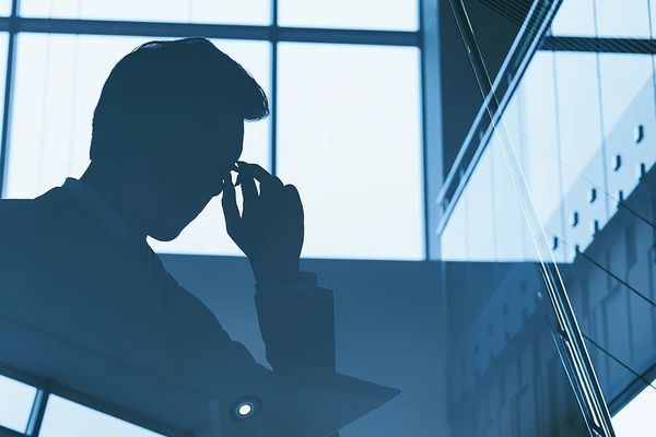 Силуэт бизнесмена на фоне офиса — символ давления регуляторов на бизнес