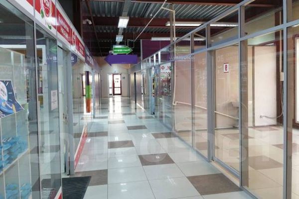 Вид пустого торгового коридора с витринами и стеклянными перегородками в небольшом торговом центре — типичный пример районной торговой недвижимости в жилых кварталах Москвы