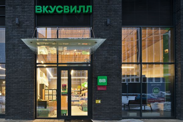 Фасад магазина «Вкусвилл» в современном здании: вид на вход с фирменной вывеской, стеклянными дверями и оформлением интерьера