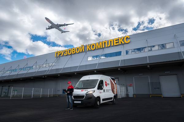 Фургон DPD у грузового комплекса с пролетающим самолётом — символ экспресс-доставки и логистических услуг по России и за рубеж
