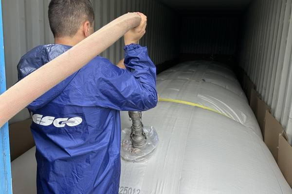 Сотрудник FESCO подключает наливной рукав при загрузке флекситанка в 40-футовый контейнер; внутри — полимерный вкладыш для перевозки неопасных жидкостей