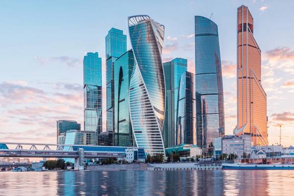 Панорама ММДЦ «Москва-Сити» на закате с башнями и пешеходным мостом «Багратион» — иллюстрация к материалу о вакантности инфраструктурного ритейла
