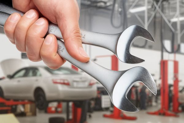 Крупный план гаечных ключей в руке на фоне автосервиса — символ роста нагрузки на станции технического обслуживания автомобилей в России
