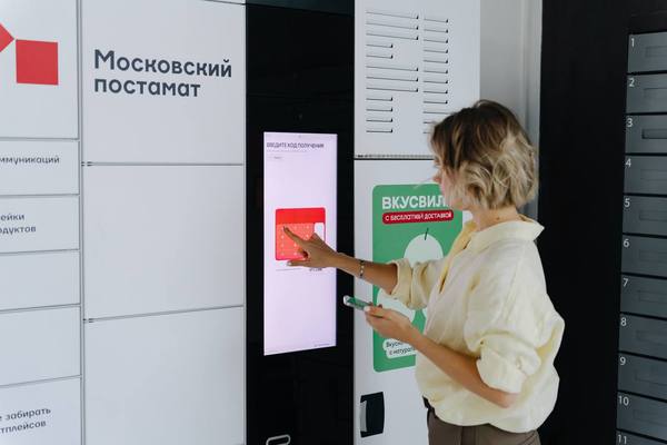 Женщина использует умный постамат с функцией охлаждения от ВкусВилл и Московского постамата для получения продуктового заказа