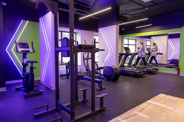 Интерьер автоматизированного фитнес-клуба XFIT Point с современными тренажёрами и неоновым освещением в ЖК «Новая Рига»