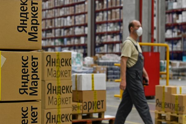 Сотрудник склада на фоне коробок с логотипом Яндекс Маркет в логистическом центре
