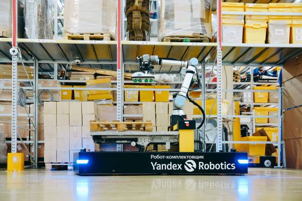 Мобильный робот-комплектовщик от Yandex Robotics на складе, с манипулятором и системой захвата, демонстрирует работу по укладке коробок в палету