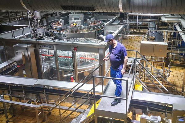 Инженер на фоне производственной линии розлива напитков на пивоваренном заводе AB InBev Efes — модернизация и переход на китайское оборудование