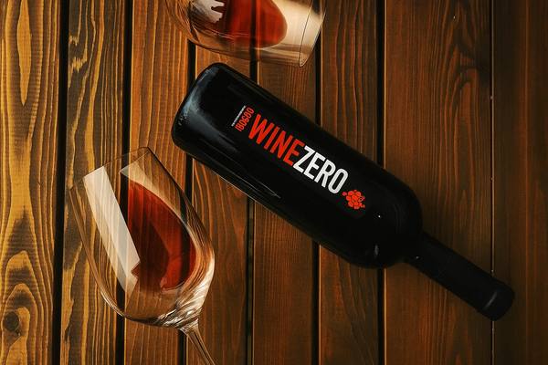 Бутылка безалкогольного вина WineZero на деревянной поверхности с двумя бокалами — иллюстрация роста спроса на вино без алкоголя в России