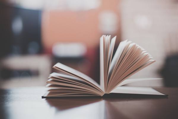 Открытая бумажная книга на столе — символ возвращения физического формата в цифровую среду. Иллюстрация перехода «Литреса» от e-book к офлайн-продажам и новой логистике.