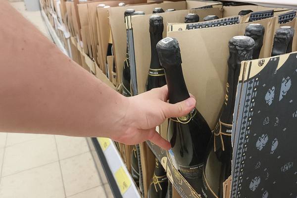Покупатель выбирает бутылку шампанского на полке супермаркета — отражение потребительского поведения и динамики спроса на игристые вина в розничной торговле