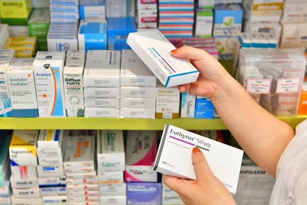 Покупатель выбирает лекарственные препараты в аптеке на фоне полок с медикаментами