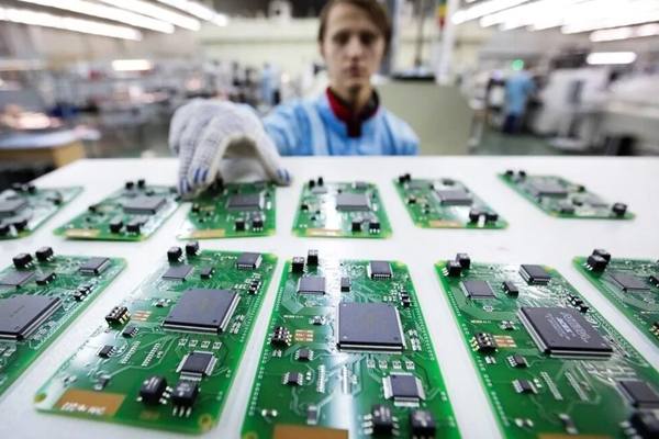 Работник в перчатках проверяет электронные микросхемы на производственной линии — символ поддержки радиоэлектроники за счёт пошлин на маркировку товаров