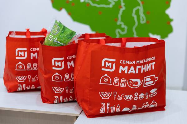 Фирменные сумки с заказами сервиса «Магнит Доставка» на фоне карты покрытия