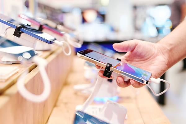 Покупатель тестирует смартфон в розничном магазине электроники — ключевая точка взаимодействия с цепочкой поставок устройств