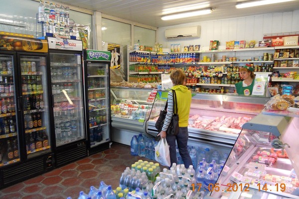 Покупатель в небольшом продуктовом магазине с прилавками и холодильниками — тренд на малые форматы ритейла в России
