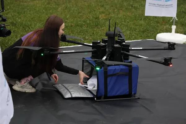 Сотрудница РВБ загружает посылку в беспилотный дрон для тестовой доставки — испытания технологии последней мили в логистике e-commerce в Санкт-Петербурге