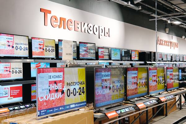 Отдел телевизоров в магазине электроники в России: витрина с моделями Smart TV и предложениями рассрочки