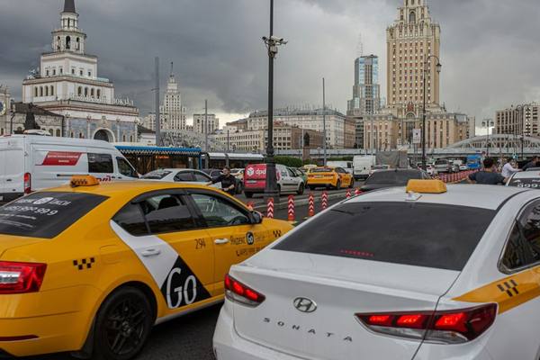 Такси и автомобили у вокзала в Москве на фоне городских зданий и небоскрёбов в пасмурную погоду