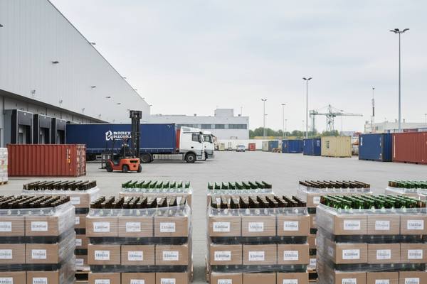 Логистический терминал с паллетами бутылочного пива и контейнерами, иллюстрация снижения импорта европейского пива в Россию из-за роста пошлин и изменений в логистике.