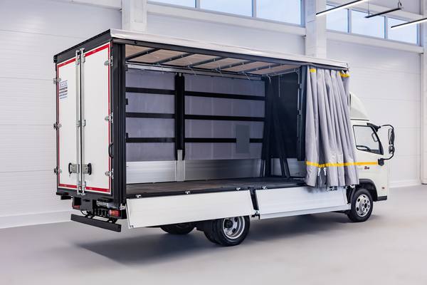 Грузовик FORLAND 3 с надстройкой «борт-штора» в пустом светлом помещении, вид сбоку с открытым тентом