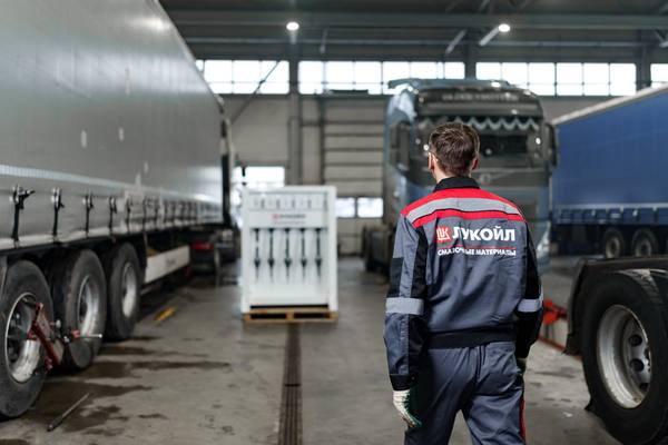 Сотрудник ЛУКОЙЛ в сервисном боксе осматривает грузовые автомобили при обслуживании автопарка и контроле смазочных материалов