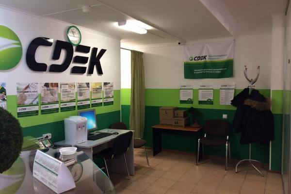 Интерьер пункта выдачи СДЭК с рабочей зоной, коробками для отправлений и фирменным оформлением компании