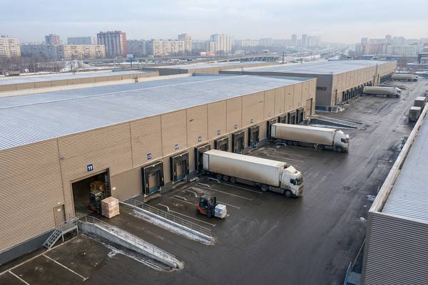 Современный складской комплекс с фурами у доковых ворот на окраине крупного российского города