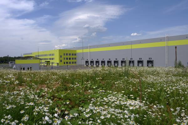 Складской комплекс «Ориентир-Запад» в Подмосковье, фасад с погрузочными воротами на фоне поля с цветами