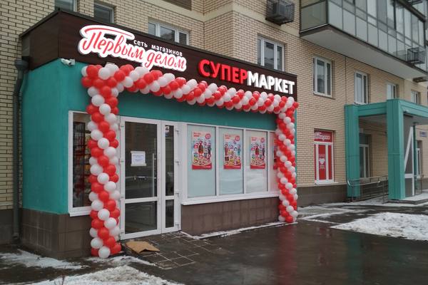 Фасад франчайзингового супермаркета «Первым делом» от сети «Дикси» с праздничным оформлением и вывеской, зима, городской жилой квартал