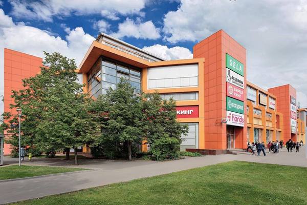 Фасад торгового центра «Ареал» в районе Беляево, Москва, с брендами арендаторов на фоне ясного неба