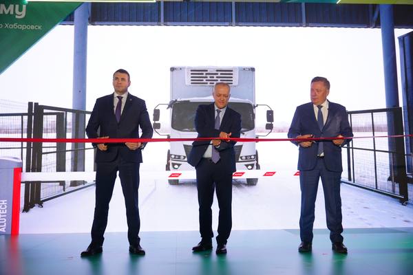 Официальное открытие распределительного центра «Пятёрочки» на Дальнем Востоке: три руководителя в деловых костюмах перерезают красную ленту на фоне грузового рефрижератора