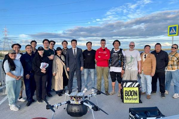 Группа участников проекта по запуску регулярных дрон‑рейсов в Якутии рядом с беспилотным летательным аппаратом на открытой площадке