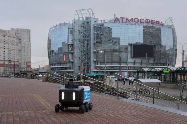 Робот-доставщик Яндекса на тротуаре у торгово-развлекательного комплекса «Атмосфера» в Приморском районе Санкт-Петербурга