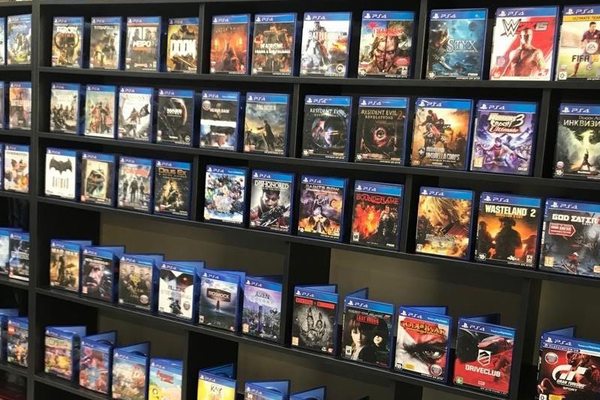 Полки магазина с большим ассортиментом физических копий видеоигр разных жанров, иллюстрирующие потребительский спрос на игровом рынке осенью