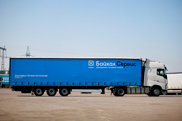 Грузовой автомобиль компании “Байкал Сервис” с синим тентом на площадке перед отправкой
