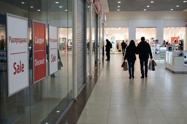 Пустоватый торговый центр в период распродаж: витрины с табличками Sale и редкие покупатели