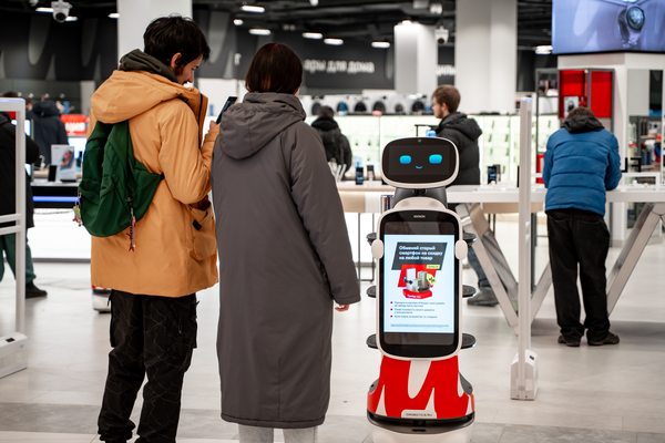 Покупатели в новом магазине М.Видео в ТРЦ «Голливуд» в Санкт-Петербурге рядом с сервисным роботом-консультантом