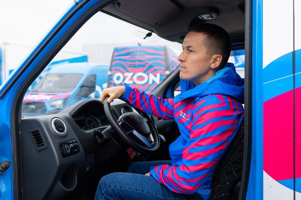Курьер Ozon за рулём автомобиля службы доставки на логистическом маршруте