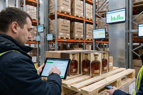 Сотрудники склада проверяют партию премиального алкоголя на паллете и проводят инвентаризацию в логистическом центре