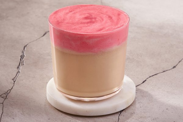 Стакан протеинового кофе с карамелью и ярлой розовой пеной, представленного в новой линейке функциональных напитков Перекрёстка.