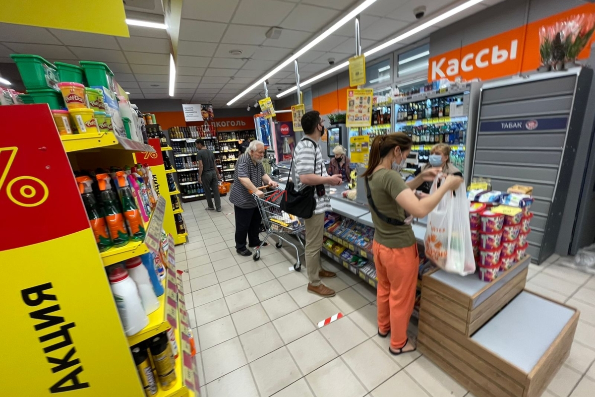 Покупатели в небольшом продуктовом магазине у кассовой зоны на фоне акционных товаров — отражение изменения потребительского поведения и падения трафика