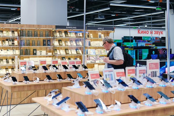 Покупатель выбирает смартфоны Samsung и других брендов в магазине электроники