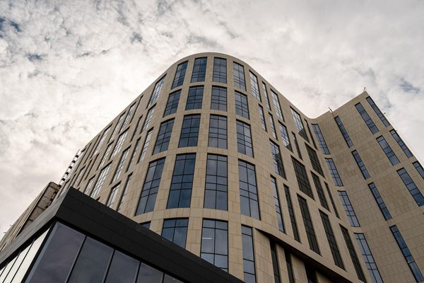 Фасад современного офисного здания в Москве, снятый снизу вверх; иллюстрация роста себестоимости строительства и развития деловой недвижимости.