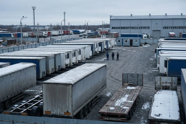 Промышленная площадка со стоящими полуприцепами в зимних условиях — иллюстрация спада рынка техники и сокращения инвестиций в автологистику