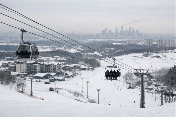Горнолыжный курорт рядом с городом — подъемник и трассы на фоне городской застройки, инфраструктура «Бобрового лога» в Красноярске