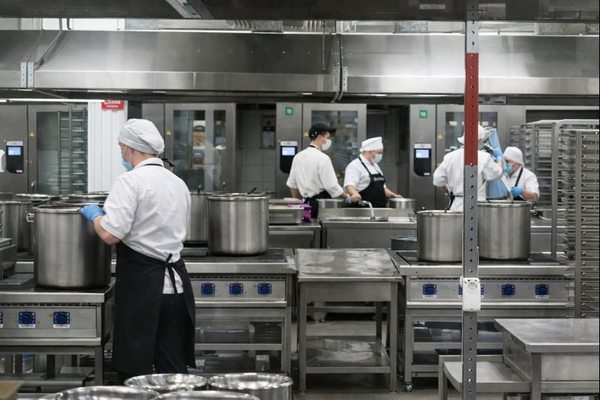 Производство готовой еды на фабрике-кухне — сотрудники на пищевом производстве и логистическая инфраструктура сервиса доставки обедов