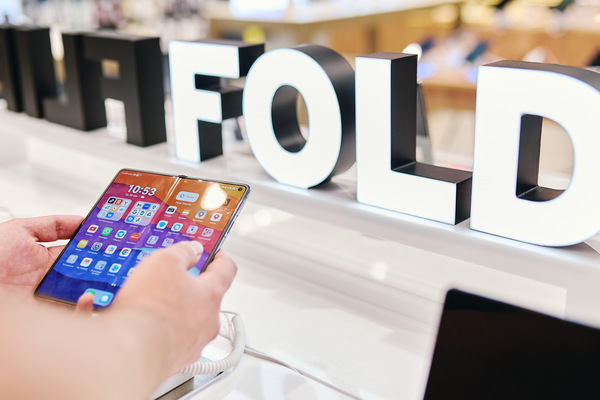 Складной смартфон с гибким экраном на витрине магазина электроники на фоне вывески FOLD, иллюстрирующий рост рынка складных устройств в России
