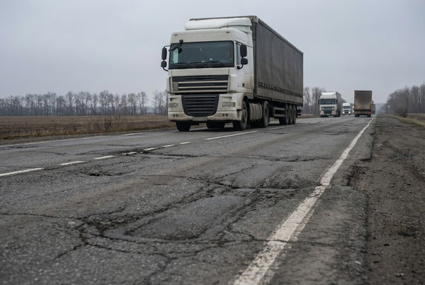грузовики на трассе с повреждённым асфальтом, состояние дорожной сети и влияние на грузоперевозки в России